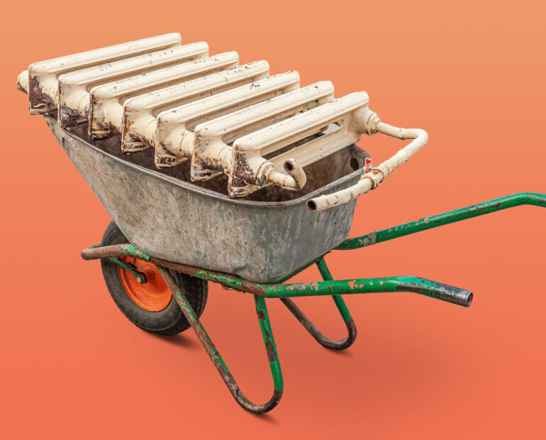 Eine Schubkarre mit einem alten gusseisernen Heizkörper für das Recycling.