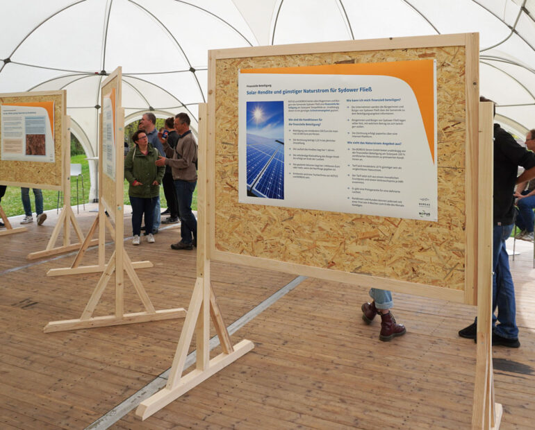 Plakatwände aus Holz zeigen Infoplakate.
